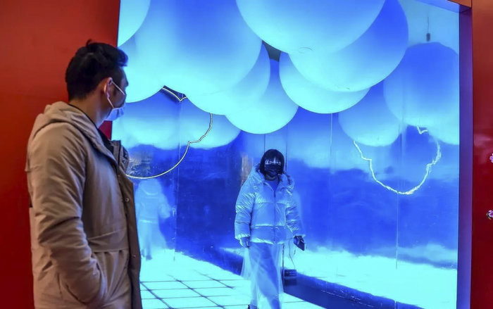 Mọi người mang khẩu trang khi đi bộ trong một trung tâm mua sắm tại Vũ Hán ngày 23/1/2020. (Ảnh: AFP – HECTOR RETAMAL)