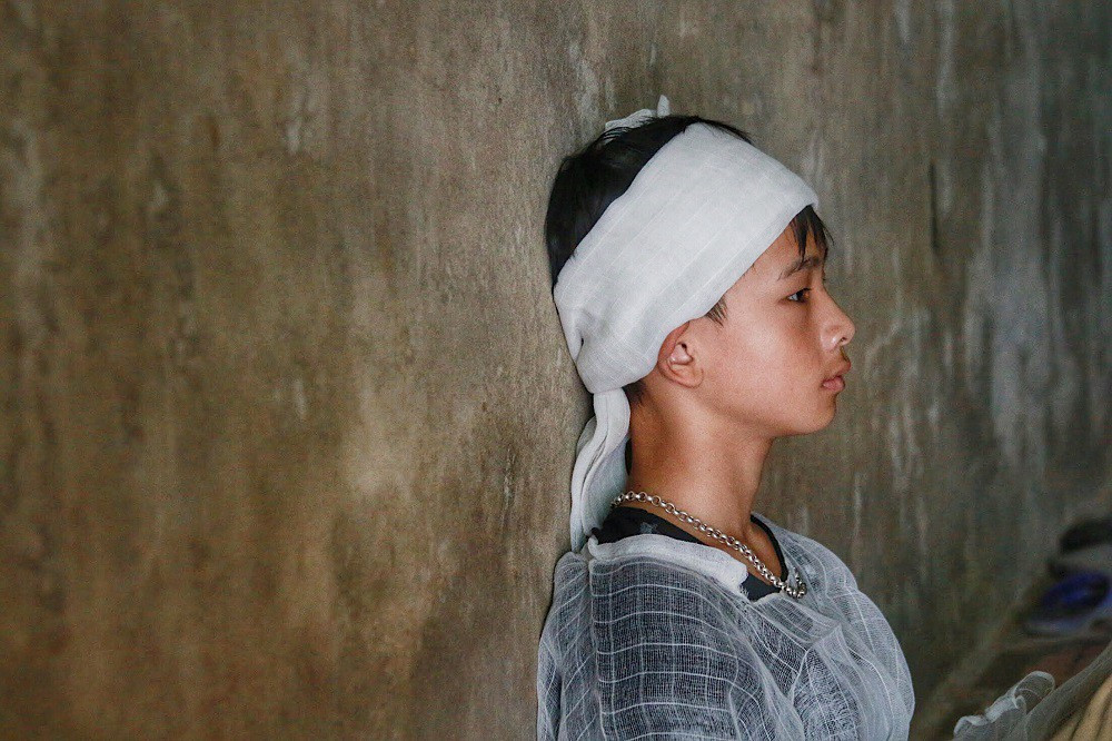 Công ngồi thẫn thờ nhìn quan tài bố mẹ.