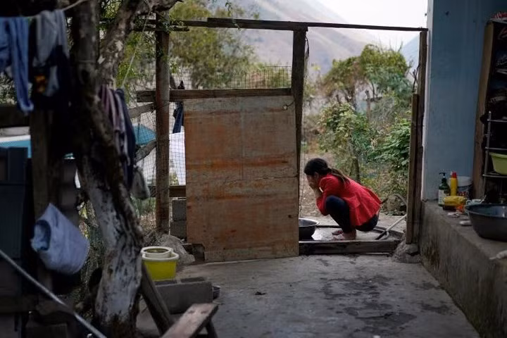 Chị Cha Huilan rửa mặt bên trong ngôi nhà của mình ở làng Lazimi.