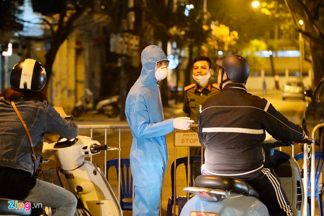 Tối cùng ngày 6/3, phố Trúc Bạch (quận Ba Đình) bị phong tỏa. Nhiều người trong trang phục bảo hộ xuất hiện. Ảnh: Phạm Thắng.
