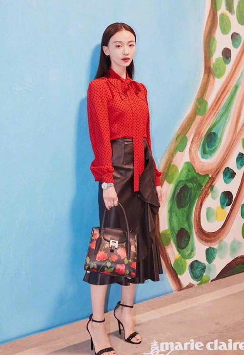 Tại show Michael Kors, cô diện set đồ thanh lịch với áo sơmi đỏ họa tiết chấm bi mix cùng chân váy da, tóc buông xõa nữ tính.