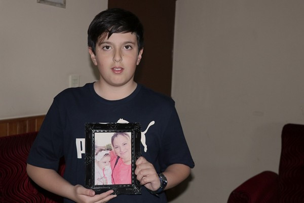 Cậu bé Miguel cầm trên tay một tấm ảnh của mẹ mình