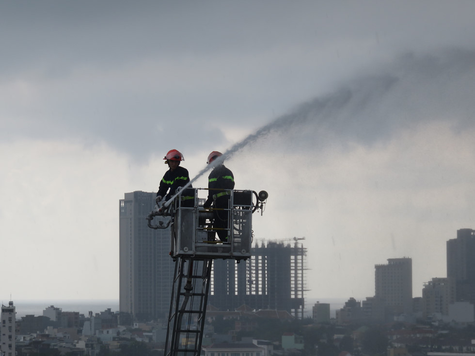 Đám cháy trên tầng 12, lực lượng chữa cháy đã điều xe thang đến hiện trường. ẢNH: NHẬT HUY.