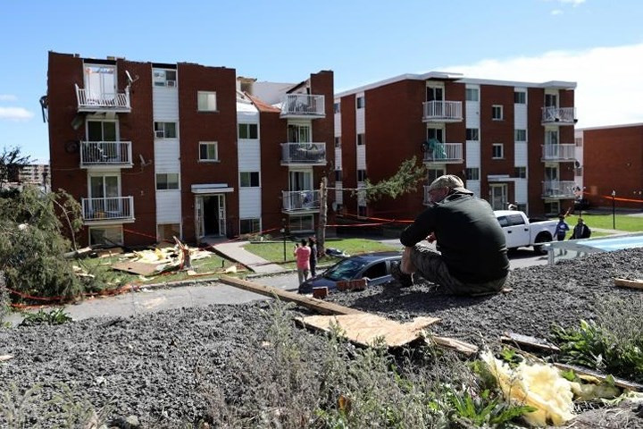 Thẫn thờ ngồi trên gò đất sau khi nhà bị hư hại vì lốc xoáy.