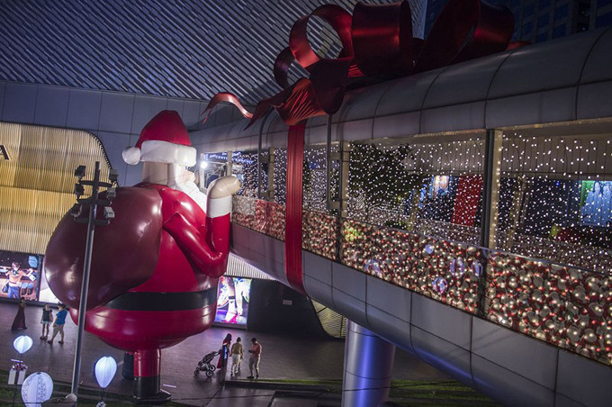 Một ông già Noel bơm hơi khổng lồ nhìn vào lối đi của trung tâm mua sắm ở Bangkok