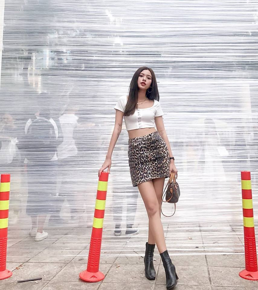 Tú Hảo năng động, trẻ trung khi kết hợp chân váy họa tiết da báo cùng áo thun crop top đơn giản và boost đen cao cổ.