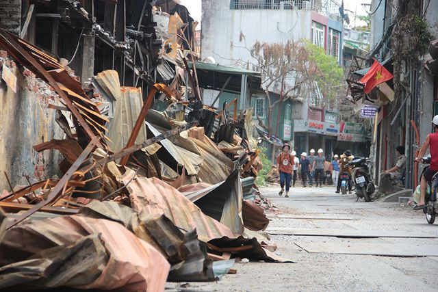 Những tấm tôn biến dạng sau đám cháy nằm ngổn ngang bên đường, khá nguy hiểm đối với người qua lại.