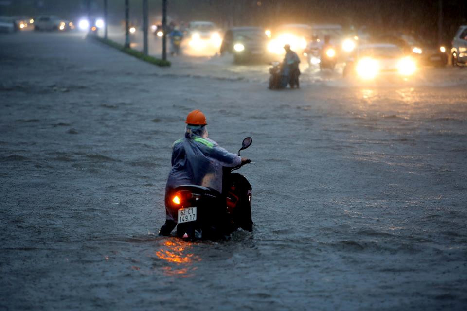 Một phụ nữ dắt xe lội nước trên đường Nguyễn Hữu Cảnh. ẢNH: NGỌC DƯƠNG.