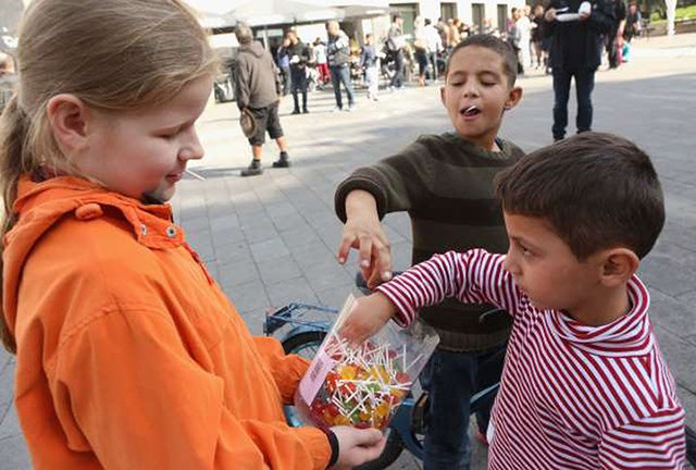 Một cô bé ở chia kẹo cho những đứa trẻ tị nạn Syria tại Hamburg, Đức ngày 19/9/2015.