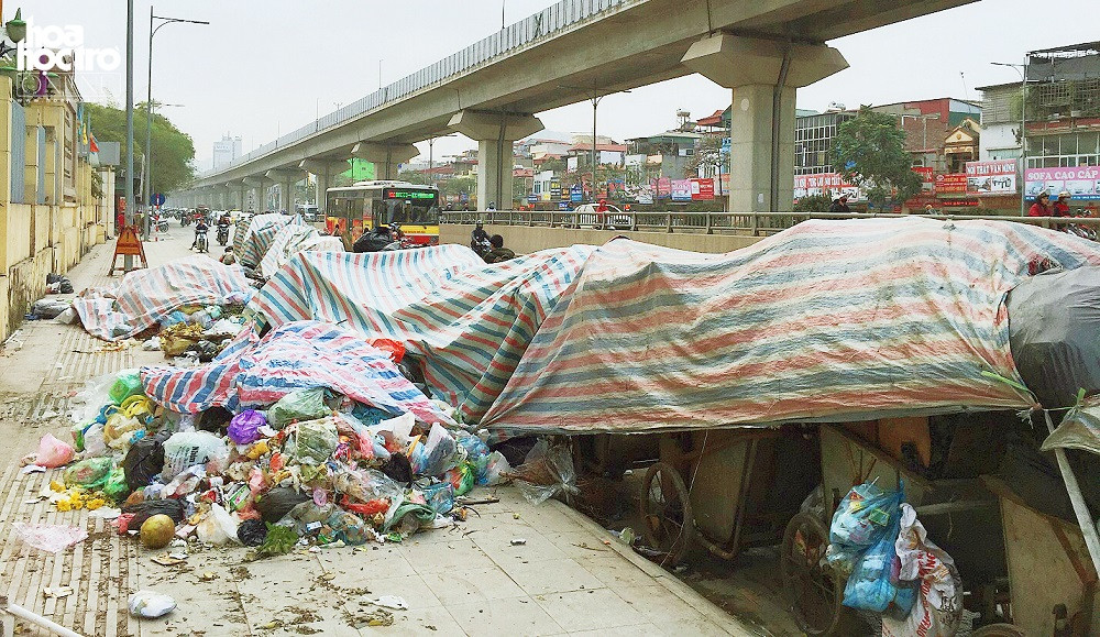 Rác thải đầu ngõ 475 Nguyễn Trãi. Rác thải trên vỉa hè và xe rác xếp dài dưới long đường.