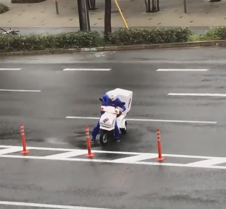 Chàng trai cố gắng chống chọi với những cơn gió cực mạnh, cố bảo vệ thùng bánh sau lưng.