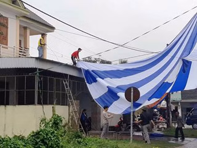 Nhiều người "đội mưa" để căng bạt phục vụ xem trận chung kết.