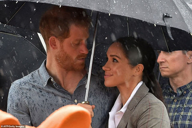 Hoàng tử Harry và cựu diễn viên điện ảnh Meghan Markle cùng che ô đứng dưới mưa.