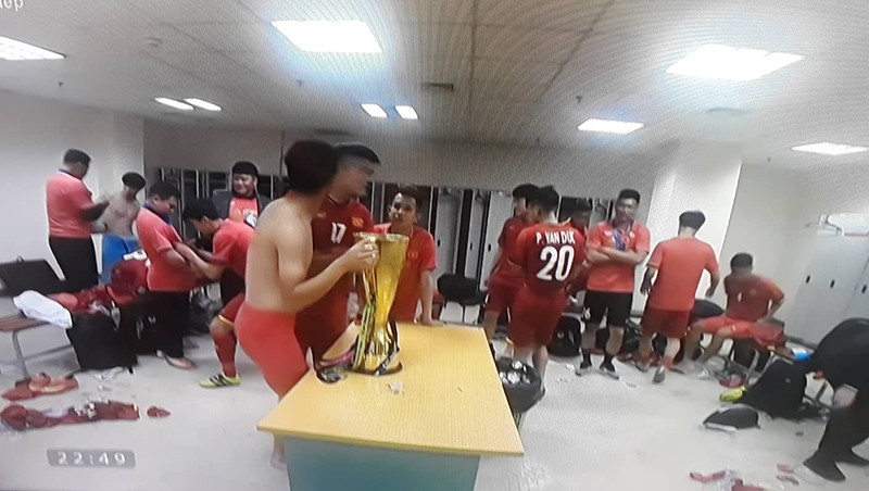 Một cầu thủ chưa kịp mặc áo đã lao ngay đến ngắm nghía và uống ngụm bia bên trong chiếc cúp.