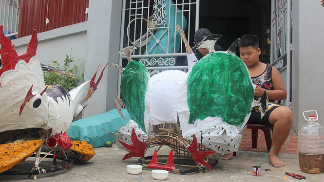 Tranh thủ giờ nghỉ, cả nhóm lại cùng nhau làm đầu lân, đầu xà. ẢNH: TRẦN MẠNH CƯỜNG.