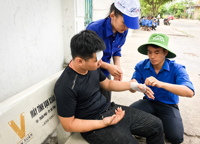 Em Nguyễn Tuấn Dũng được các sinh viên tình nguyện tại điểm thi băng bó lại vết thương. ẢNH: TÂN KỲ