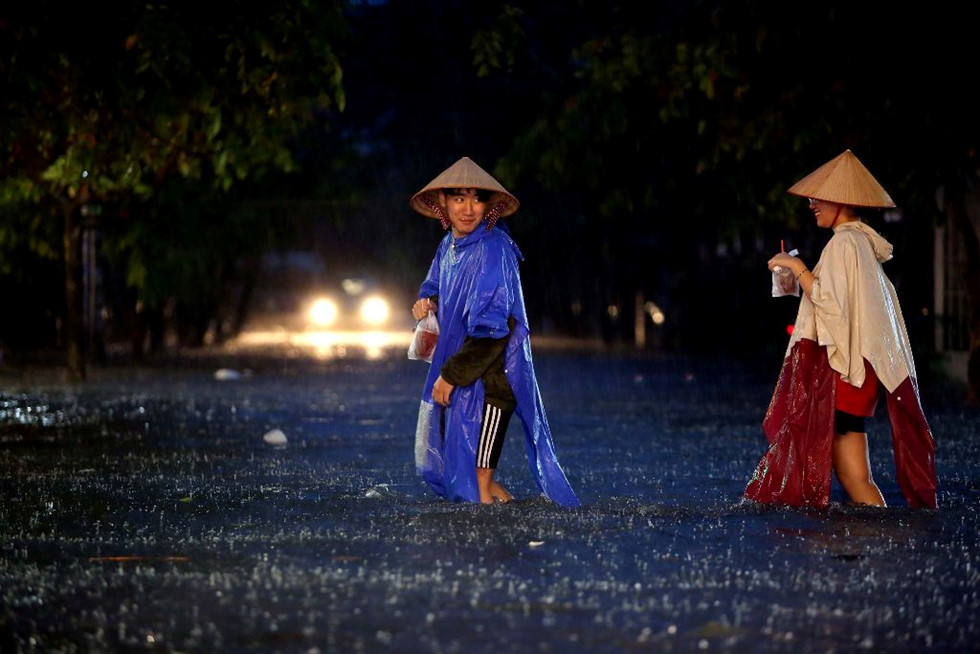 Hai người bạn trẻ lội nước trên đường Quốc Hương (Q.2). ẢNH: NGỌC DƯƠNG.