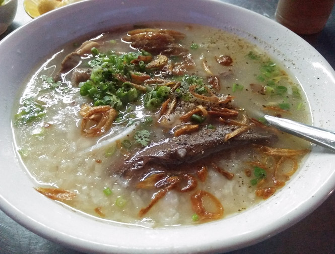Tô cháo hấp dẫn với đầy đủ thịt, huyết và hành, ngò, tiêu, hành phi.