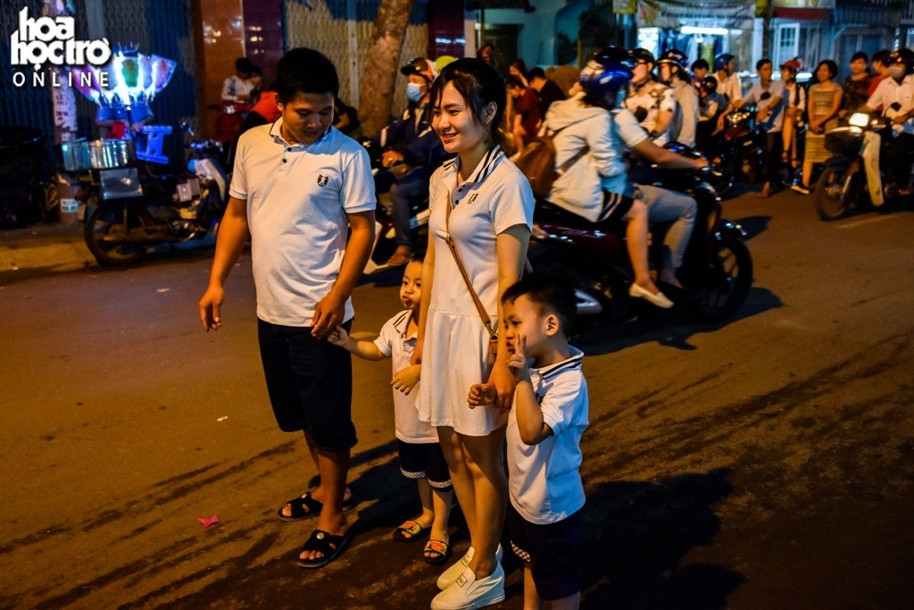 Một gia đình mặc đồ giống nhau, hào hứng đứng lại bên đường ở chụp ảnh.