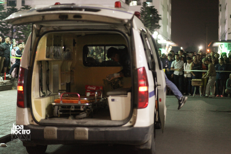 Lực lượng pháp y di chuyển thi thể của cháu bé (được đặt trong thùng giấy đỏ) vào xe cứu thương.