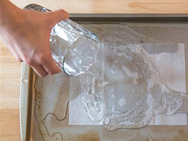 Cho tờ giấy dùng trong máy sấy quần áo vào khay nướng là cách làm sạch khay cực kỳ dễ dàng.