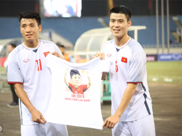 Bùi Tiến Dũng và Duy Mạnh chuẩn bị một chiếc áo với slogan "Ỉn ơi, mau trở lại nhé".