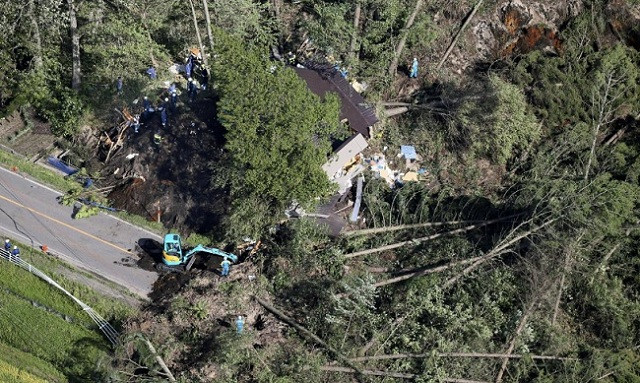 Nhà cửa bị chôn vùi trong đất đá và cây. Ảnh: Reuters