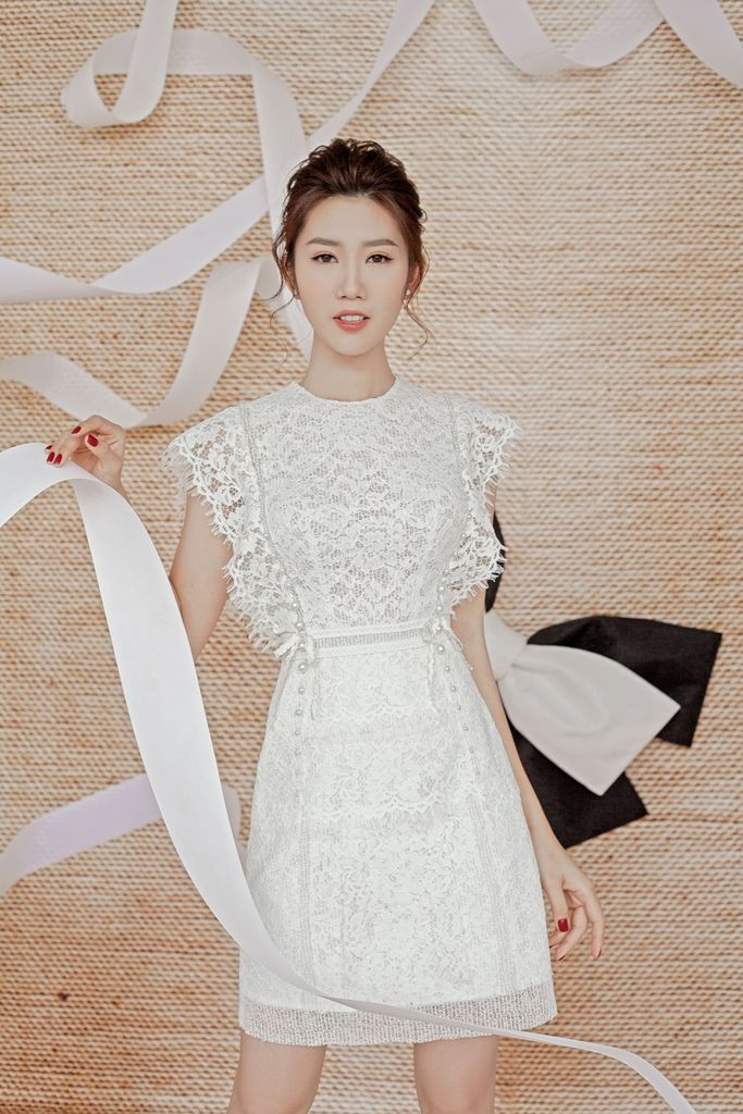 Thiết kế sử dụng các kĩ thuật ghép ren, đắp ren,… mang lại vẻ mới mẻ. Nhờ phần tay áo ren cách điệu, hai đường đính hạt chạy dọc từ vai xuống chân váy tạo sự liên kết cho bộ trang phục.