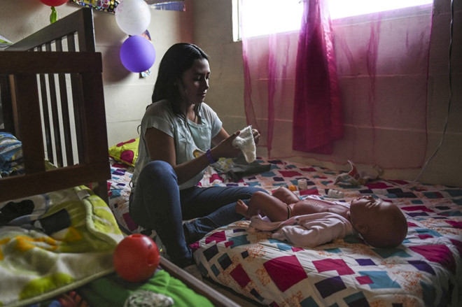 Một nữ sinh chăm sóc cho em bé robot tại nhà. Ảnh: AFP.