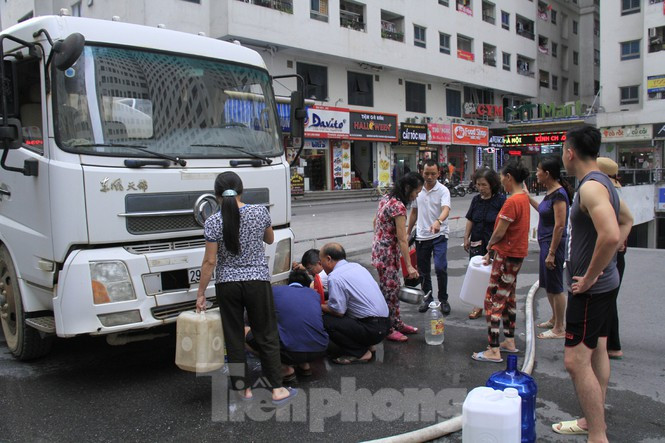 Trong phần sân chung khu chung cư HH Linh Đàm, nhiều người dân tập trung lấy nước miễn phí. Nhiều người đã lấy đầy các can, thùng nhựa chuẩn bị mang về nhà. Ảnh: Trường Phong.