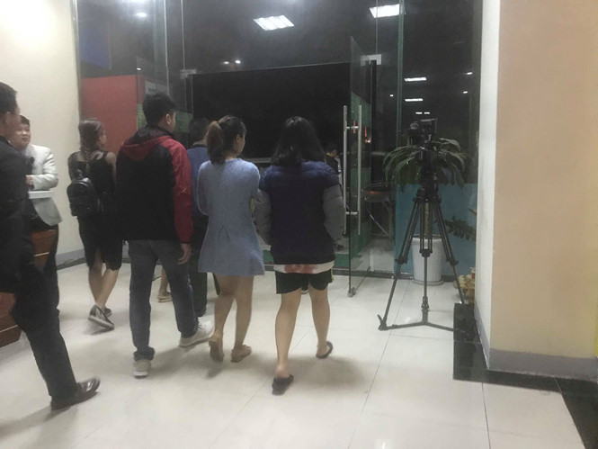 Nữ bệnh nhân (mặc áo gió bên phải) được lực lượng chức năng đưa xuống xe cứu thương, vạt áo sau vẫn còn vết máu đã khô. ẢNH: TRẦN CƯỜNG.