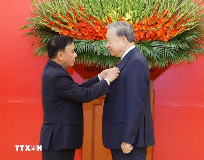Đồng chí Trần Cẩm Tú, Ủy viên Bộ Chính trị, Thường trực Ban Bí thư trao Huy hiệu Đảng và tặng hoa chúc mừng Tổng Bí thư Tô Lâm. (Ảnh: Thống Nhất/TTXVN)