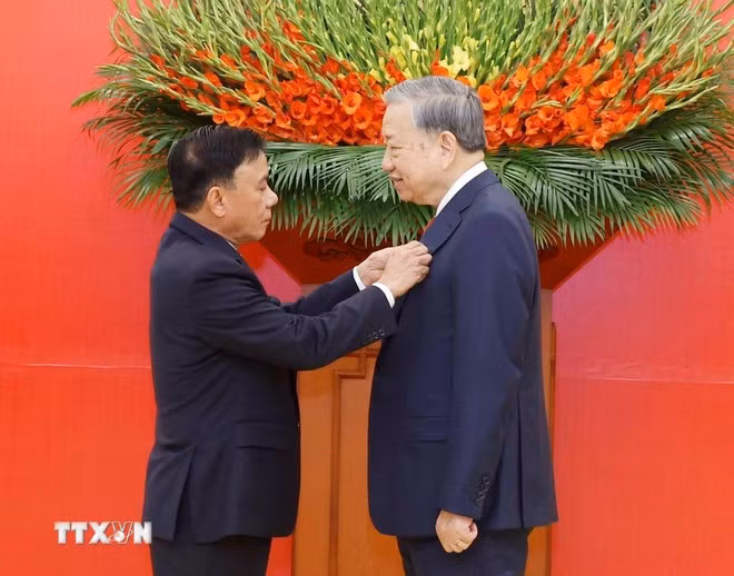 Đồng chí Trần Cẩm Tú, Ủy viên Bộ Chính trị, Thường trực Ban Bí thư trao Huy hiệu Đảng và tặng hoa chúc mừng Tổng Bí thư Tô Lâm. (Ảnh: Thống Nhất/TTXVN)