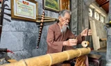 Cụ Chu Văn Thim chơi đàn bầu tự làm bằng ống bương tại đền Thái Vi Ảnh: Đình Minh 
