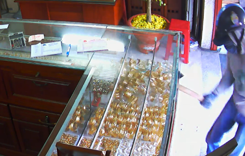 Tên cướp dùng búa đẽo đập vỡ tủ kính hốt đi nhiều nữ trang. Ảnh: Trích từ camera tiệm vàng 