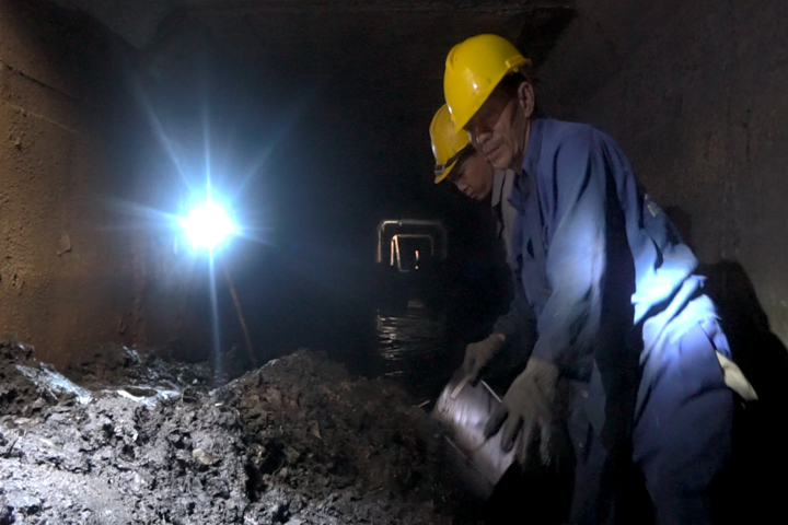 Công nhân dầm mình trong cống móc bùn trước mùa mưa ở Sài Gòn