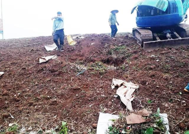 Công nhân chôn lấp rác vào hố được đào ngay trong thân đê