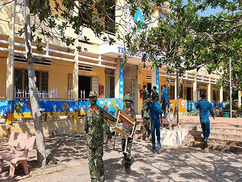 Lực lượng chức năng dọn dẹp để chuẩn bị cho khu vực cách ly Trường THCS Phú Lạc. Ảnh: Huỳnh Thuận-Ka My