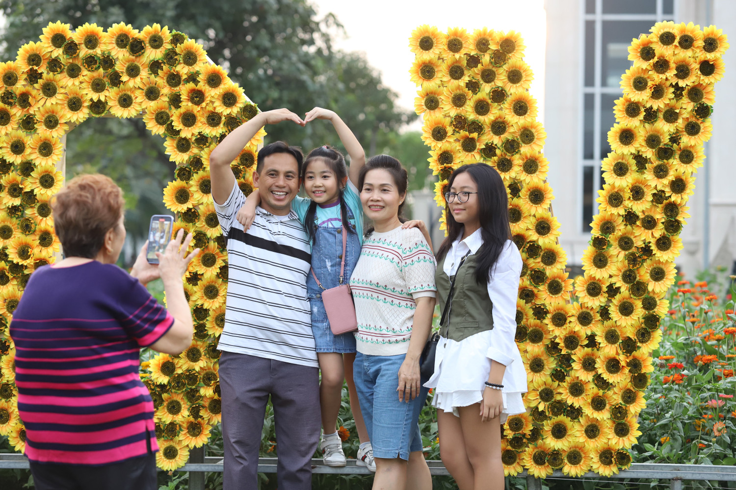 Một gia đình nhiều thế hệ chụp ảnh vui vẻ tại một tiểu cảnh hoa hướng dương. Một gia đình nhiều thế hệ chụp ảnh vui vẻ tại một tiểu cảnh hoa hướng dương.