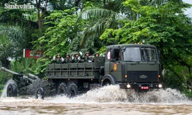 Người dân lội nước cổ vũ dàn xe khí tài quân sự vượt đường ngập 