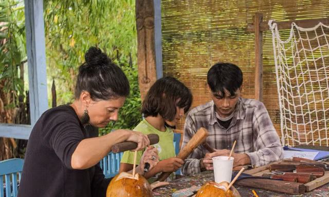 Du khách nước ngoài tự tay tạo ra tác phẩm cho riêng mình từ củi lũ. Ảnh: Văn Nhất