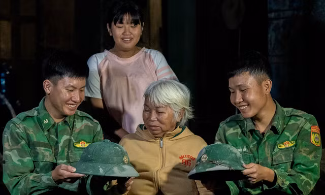 Hai người lính trẻ chụp ảnh lưu niệm, chia tay gia đình cụ Ngô Thị Lỡ với những chiếc mũ cối dính xi măng, có chiếc đứt dây Ảnh: Lê Văn Chương 