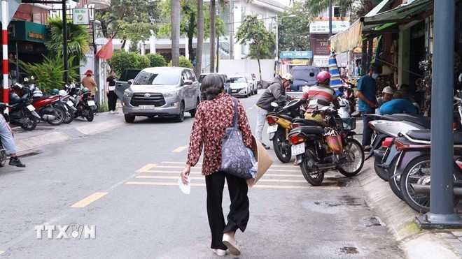 Một ngày của bà giáo Ba bắt đầu từ 6 giờ sáng đi bán vé số dọc khắp các tuyến đường thành phố. Ảnh: Huyền Trang/TTXVN.