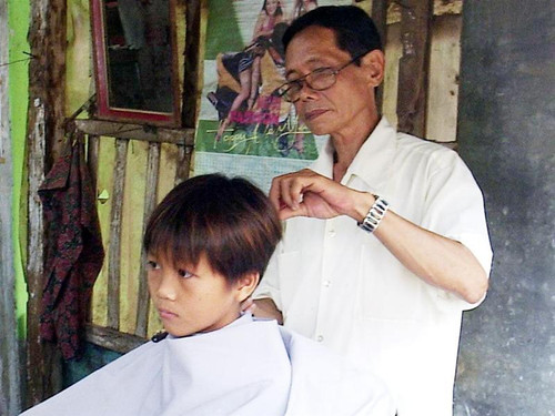 Ông Dương Văn Sinh đang cắt tóc cho một học sinh