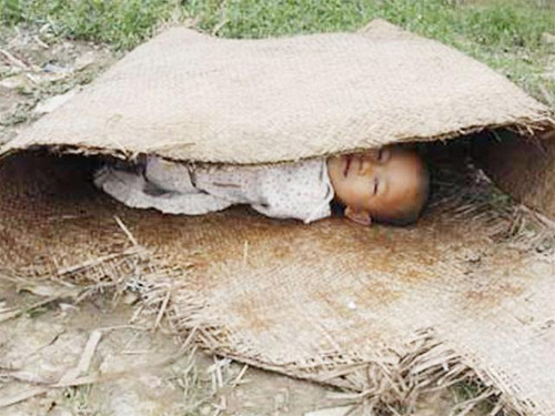 Cháu bé ngủ trưa bên đường làng ở vùng bị bão Nargis tàn phá Ảnh: Reuters