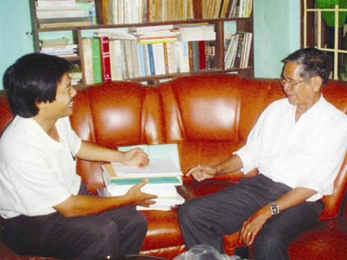 Nhà văn Y Điêng (bên phải) với chồng bản thảo sử thi Tây Nguyên đã dịch sang tiếng Ê Đê