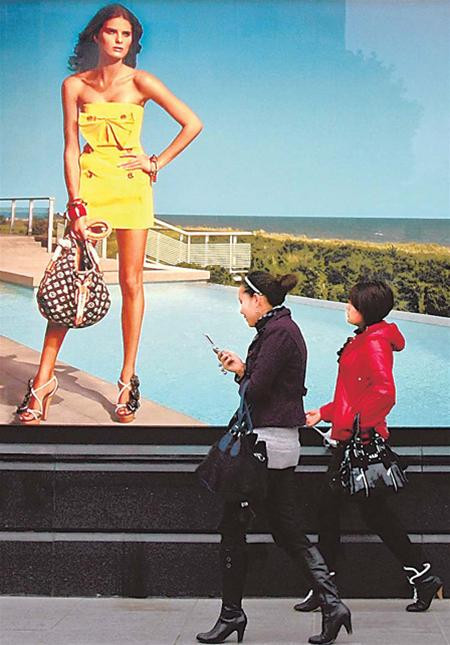 Hai cô gái Trung Quốc đi dưới tấm biển quảng cáo của thương hiệu thời trang xa xỉ Louis Vuitton. (Ảnh Chinadaily) Hai cô gái Trung Quốc đi dưới tấm biển quảng cáo của thương hiệu thời trang xa xỉ Louis Vuitton. (Ảnh Chinadaily)