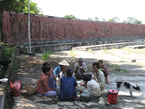 Bà con nông dân Hòn Đất ăn cơm trưa bên bức phù điêu miêu tả cuộc chiến đấu khốc liệt ngày nào