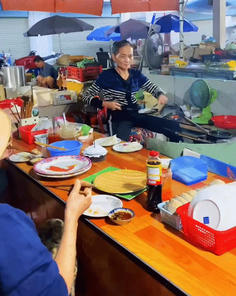 Người phụ nữ lớn tuổi thực hiện động tác đổ bánh xèo điệu nghệ khiến du khách thích thú.