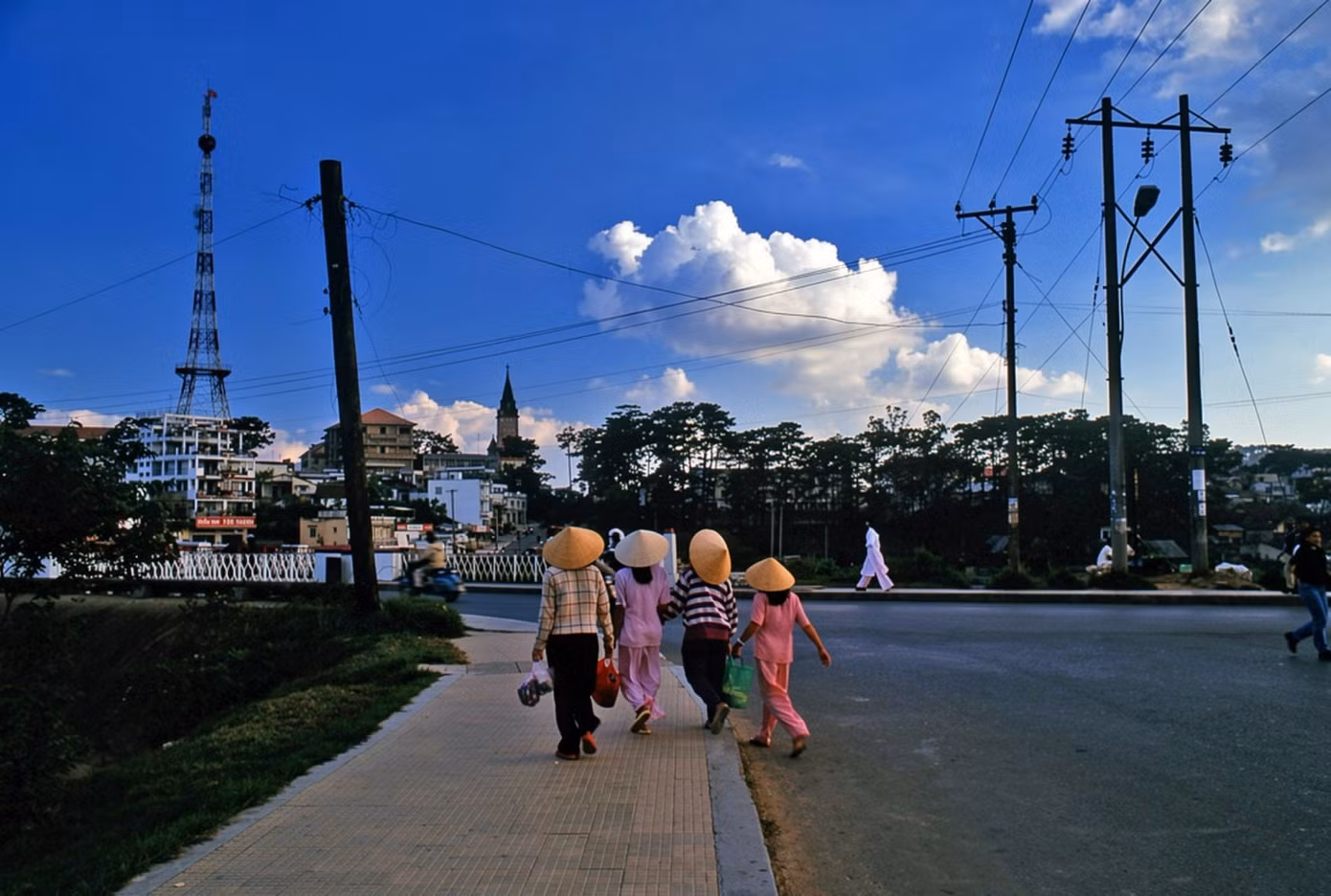 Người dân dạo bộ bên bờ hồ Xuân Hương, phía xa là tháp chuông nhà thờ Con Gà. Con đường chạy quanh hồ uốn theo địa hình, nối khu vực trung tâm với những khoảng xanh và các công trình nghỉ dưỡng, công cộng. Nhờ sự xuất hiện của quảng trường Lâm Viên (nay thuộc phường Xuân Hương - Đà Lạt) năm 2016, khu vực quanh hồ Xuân Hương trở nên nhộn nhịp vào mỗi buổi tối.